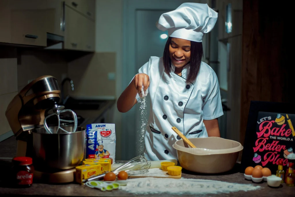 "A female chef wearing a white apron baking with various ingredients in a modern kitchen."